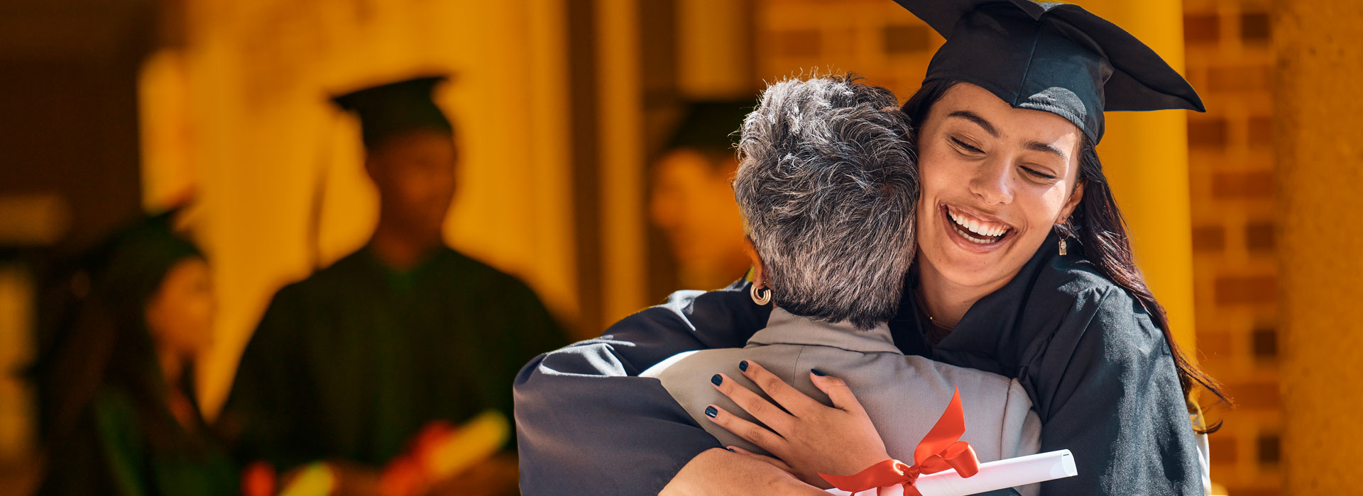 A female international student graduating hugs a friend or relative.