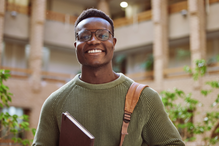Nigerian student standing on a university campus with books, symbolising studying in the UK from Nigeria