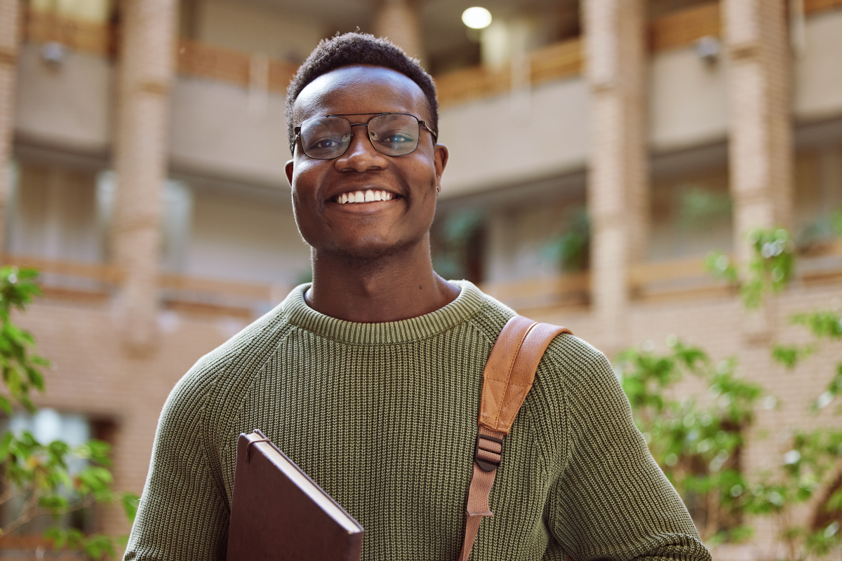 Nigerian student standing on a university campus with books, symbolising studying in the UK from Nigeria