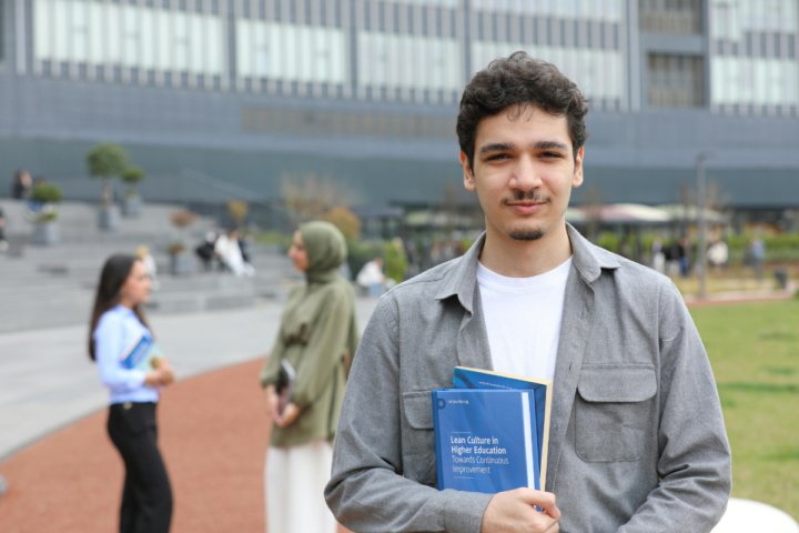 Qatari student holding books on a UK university campus